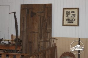 Display of tools from the camp and a sign during the mining, urging "Live and let live! Resume Hydraulic Mining."